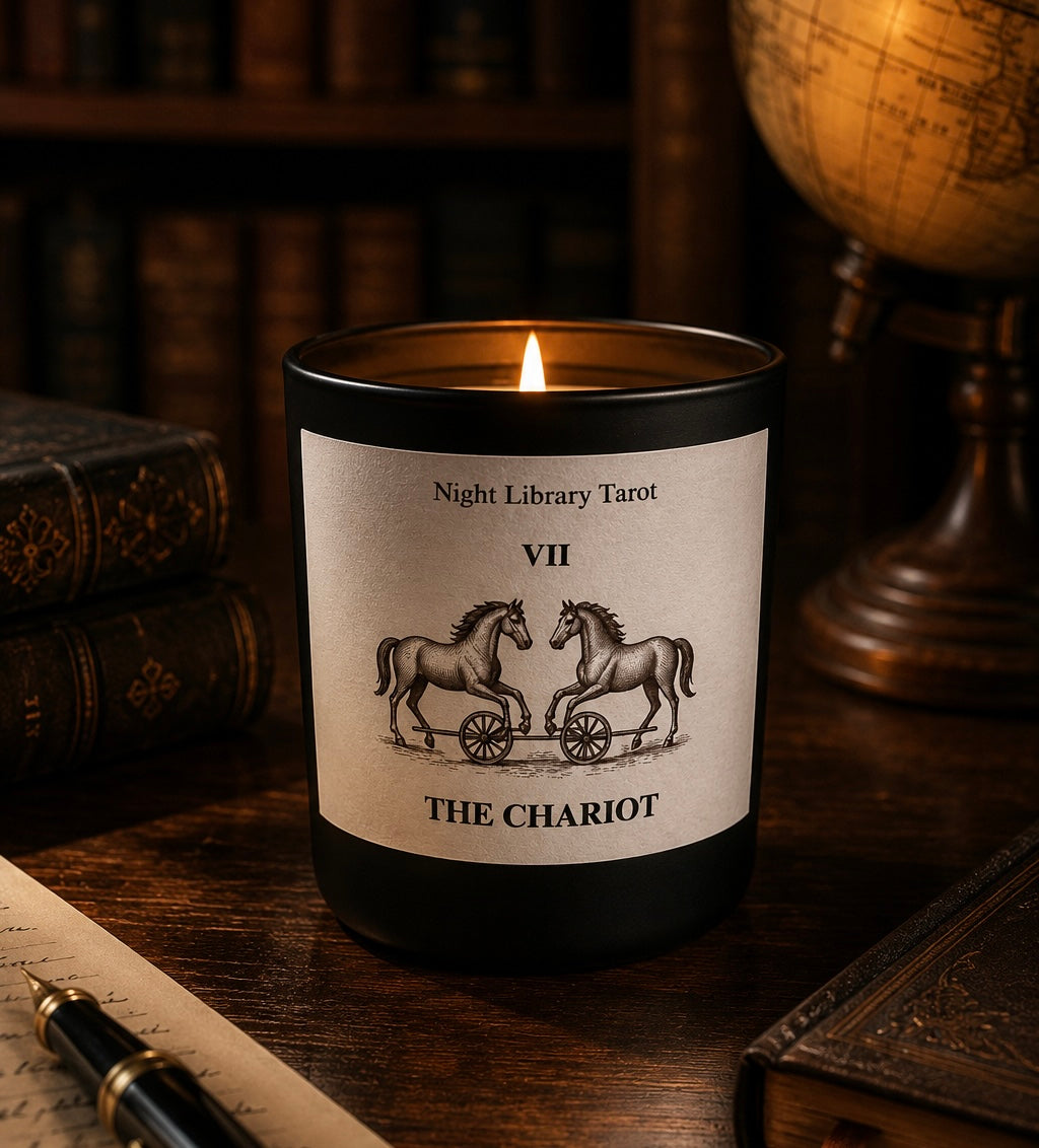 Candle with 'The Chariot' tarot card design on a wooden surface with books and a globe in the background.