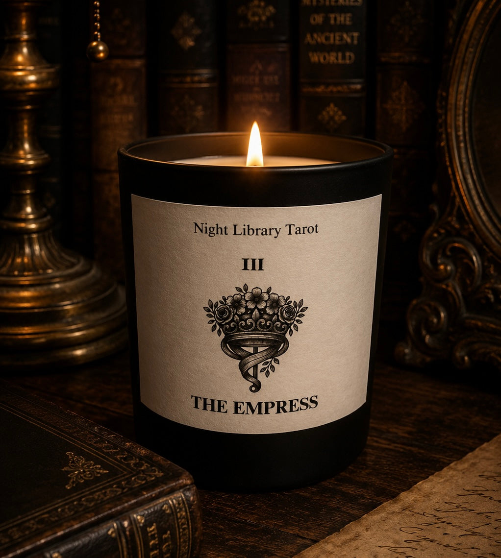 Candle labeled 'The Empress' from Night Library Tarot in a dark setting with books. Luxury candle tarot inspired.